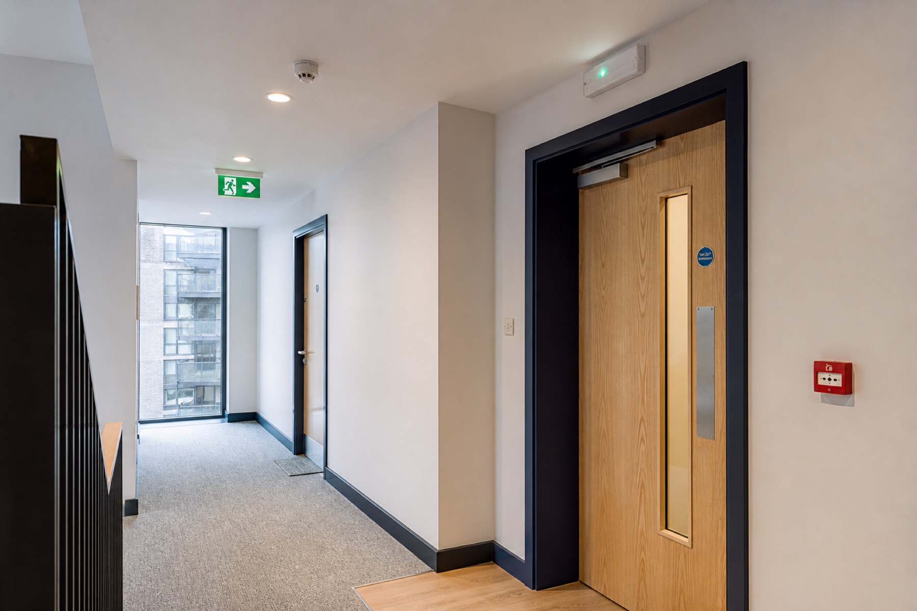 Modern managed corridor with emergency lighting, exit signage and fire doors